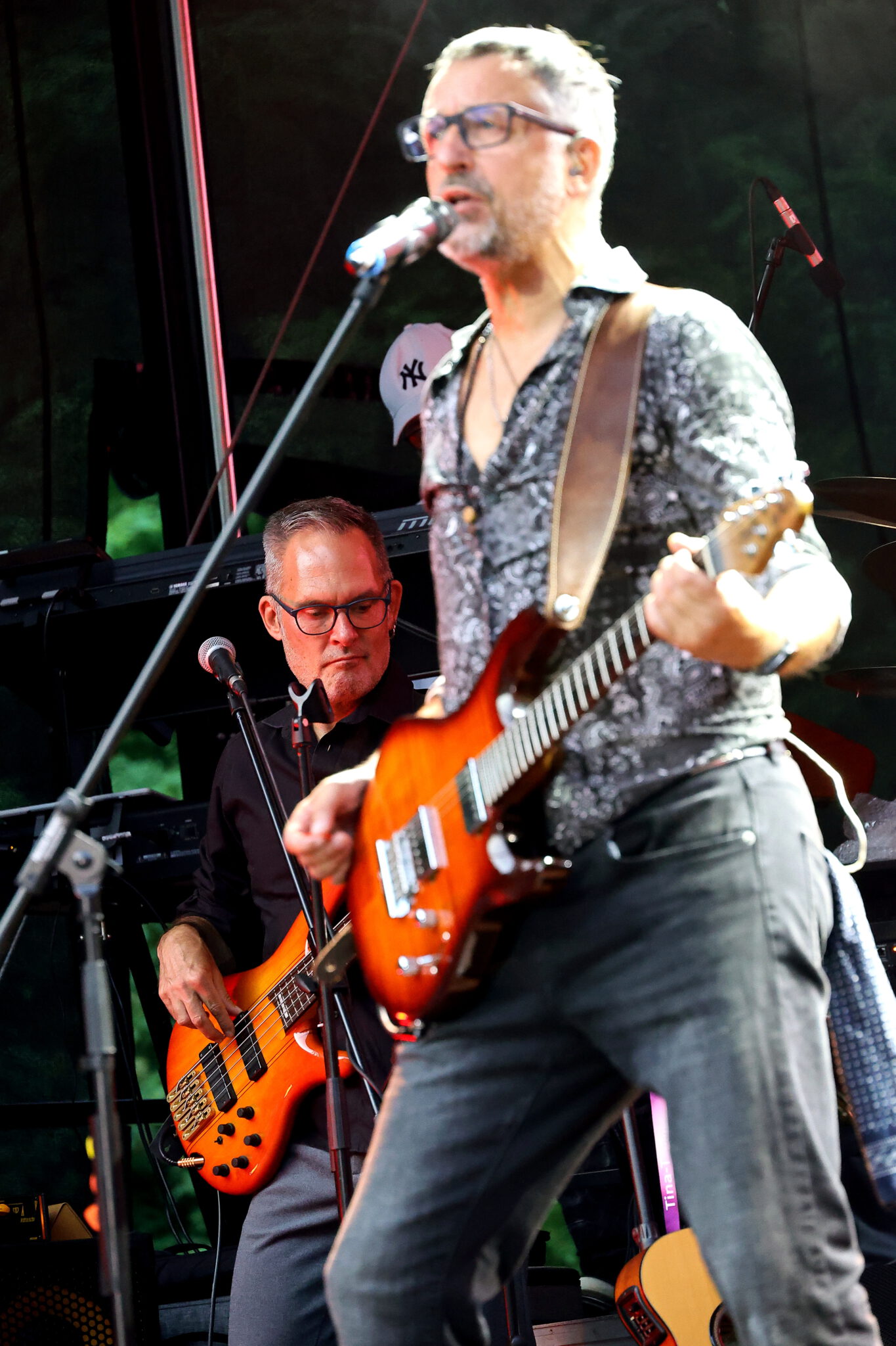 a man playing guitar on stage with a microphone and a man playing guitar